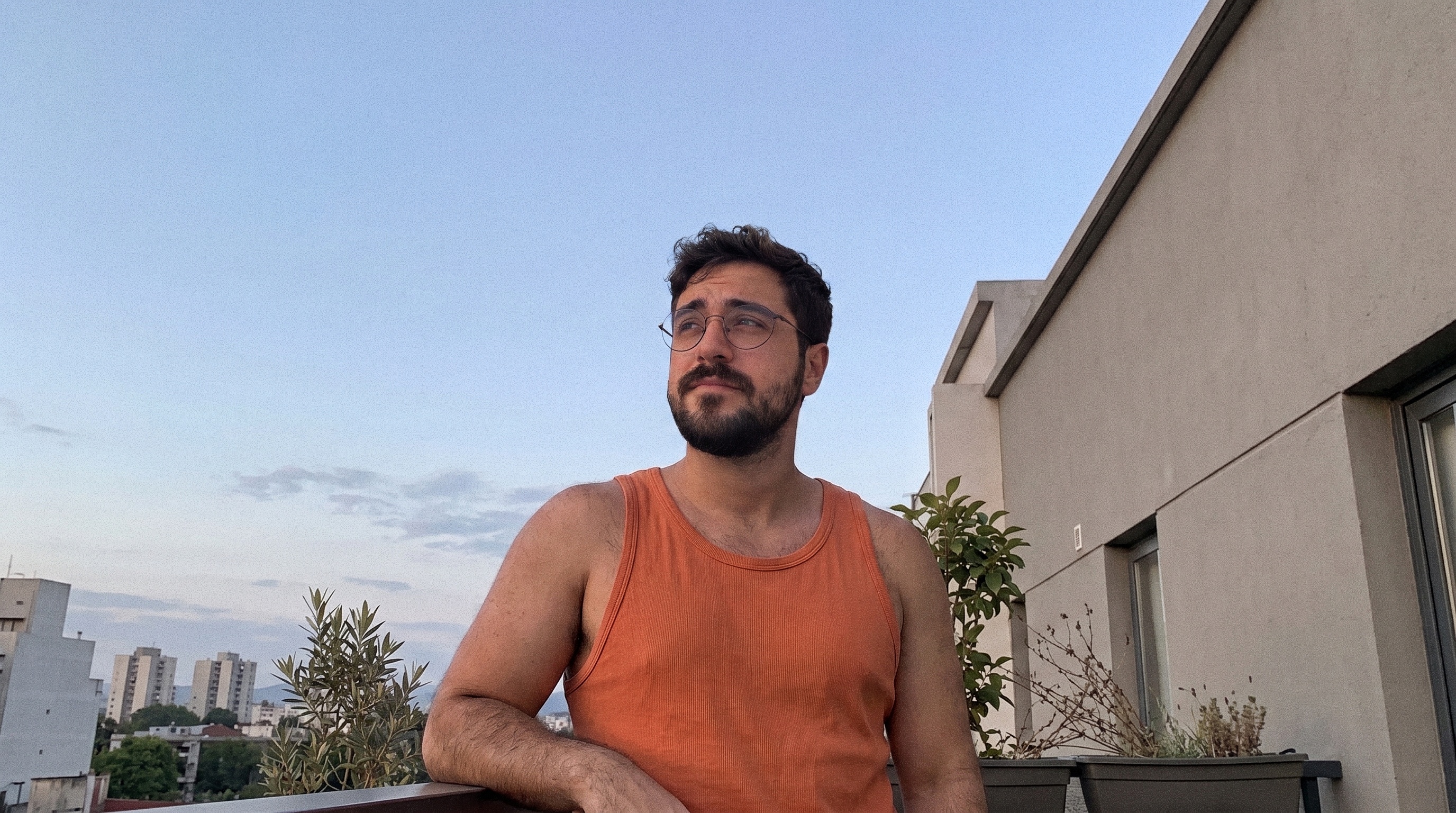 Adriel on a balcony at dusk, looking off to the side