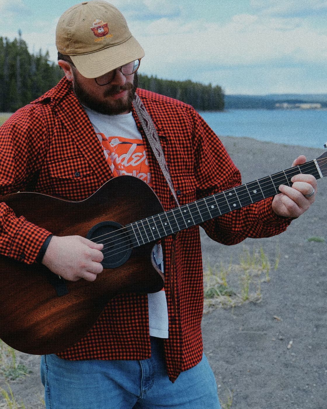 Spencer Sanders playing guitar by a lake